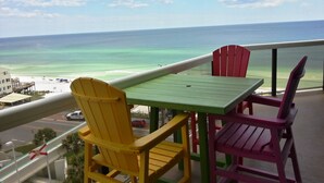 Een balkon met een tafel en stoelen met uitzicht op een strand.