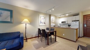 A compact living space with a dining area, kitchenette, and a sofa.