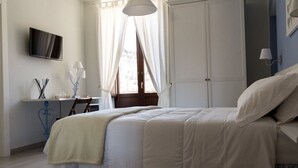 Une chambre à coucher avec un lit, un bureau, une télévision et une armoire.