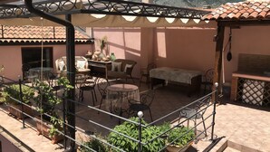 Une terrasse aménagée avec du mobilier d’extérieur, des plantes en pot et une vue sur une montagne.