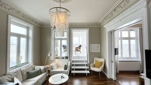 Un vaste salon doté d’un haut plafond, de grandes fenêtres et d’un lustre.