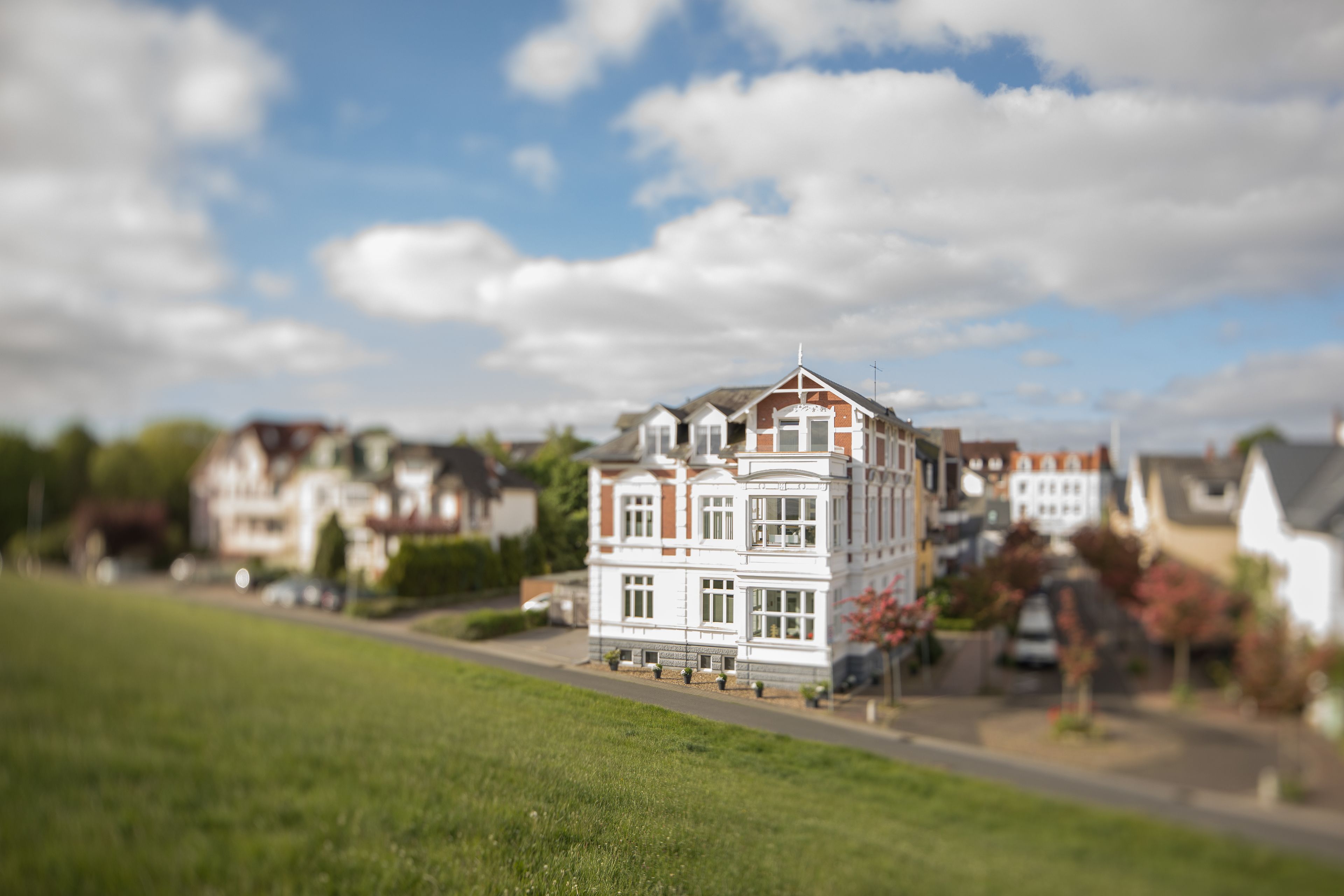 Ein Modell eines mehrstöckigen Gebäudes mit einer symmetrischen Fassade, großen Fenstern und einem zentralen Eingang.