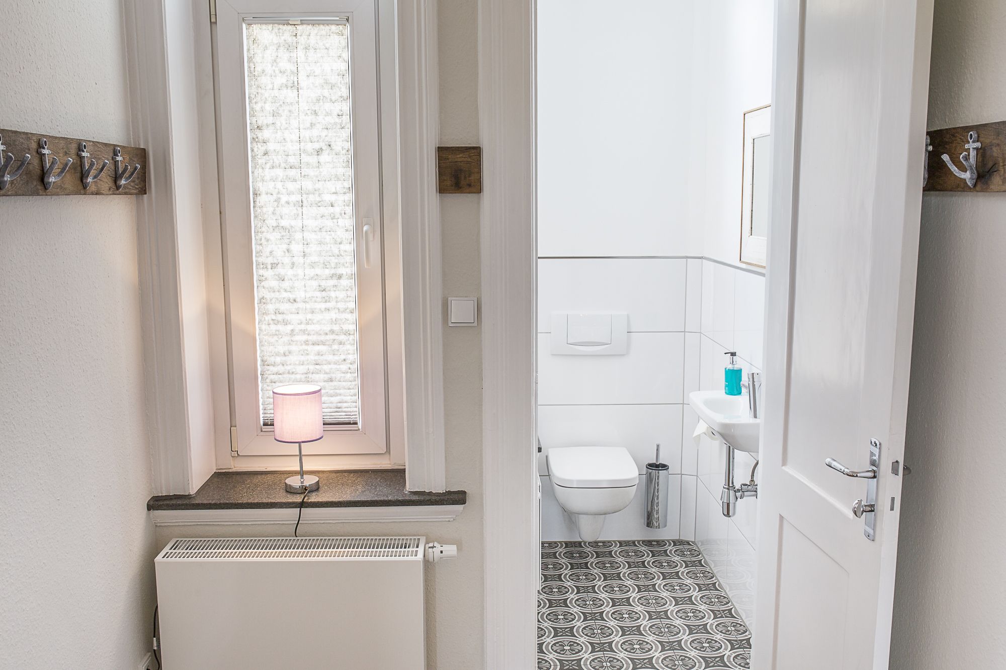 A bathroom with a toilet, sink, and patterned floor tiles.