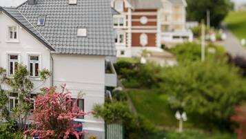 A residential area with houses, a parked car, and a pink flowering tree.