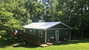 A small, single-story building with a metal roof, a front porch, and a flag. - Charming Lake Barkley cabin (Cadiz)