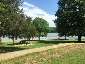 Un parco con tavoli da picnic, un sentiero e un lago.