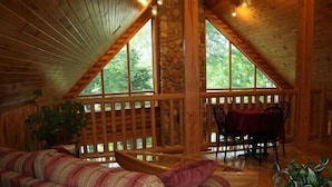 A cozy cabin with a wooden interior, a stone wall, and a dining area with a table and chairs. - Red Bank Lodge - Red Bank, New Brunswick (Sillikers)