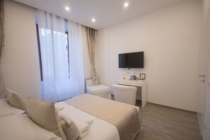 Ein Hotelzimmer mit zwei Betten, einem Schreibtisch, einem Fernseher und einem fenster mit Vorhängen.