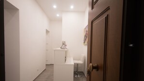 A hallway with a reception desk, a white chair, and a door.