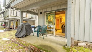 A covered patio with outdoor furniture, a grill, and a sliding glass door leading to a room.
