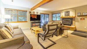 A spacious living room with a fireplace, a sofa set, a television, and a dining area.