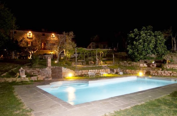 Relax by the serene pool surrounded by lush greenery and a stone wall.