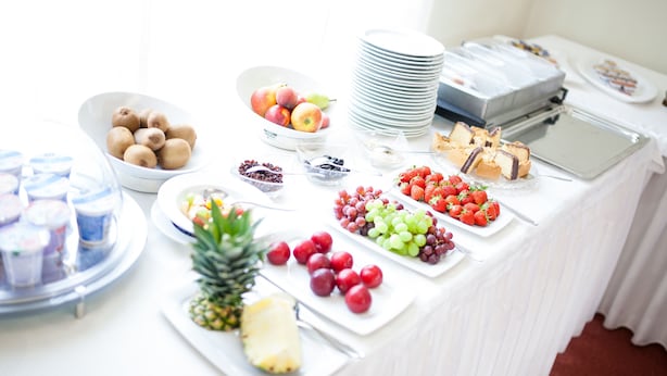 Een buffet met diverse soorten fruit, desserts en drankjes.