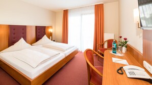 Een hotelkamer met een bed, een bureau met telefoon, een stoel en een televisie.