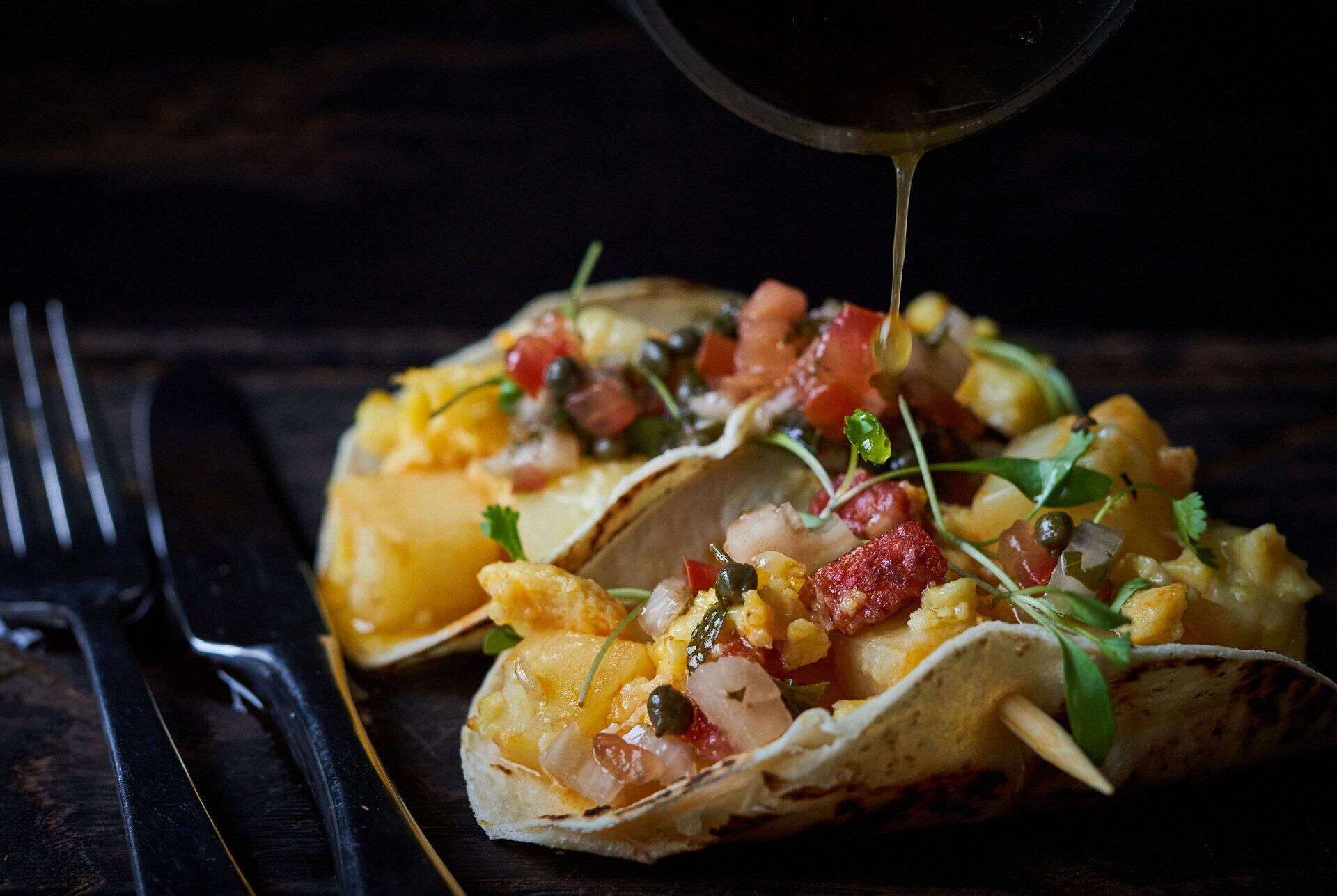 Un taco con ingredientes y salsa vertida encima.