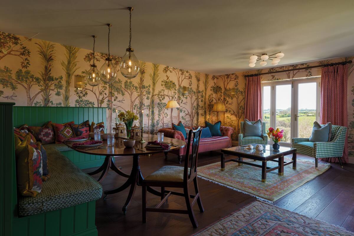 A cozy living room with a green bench, a wooden coffee table, and a sofa with colorful cushions.
