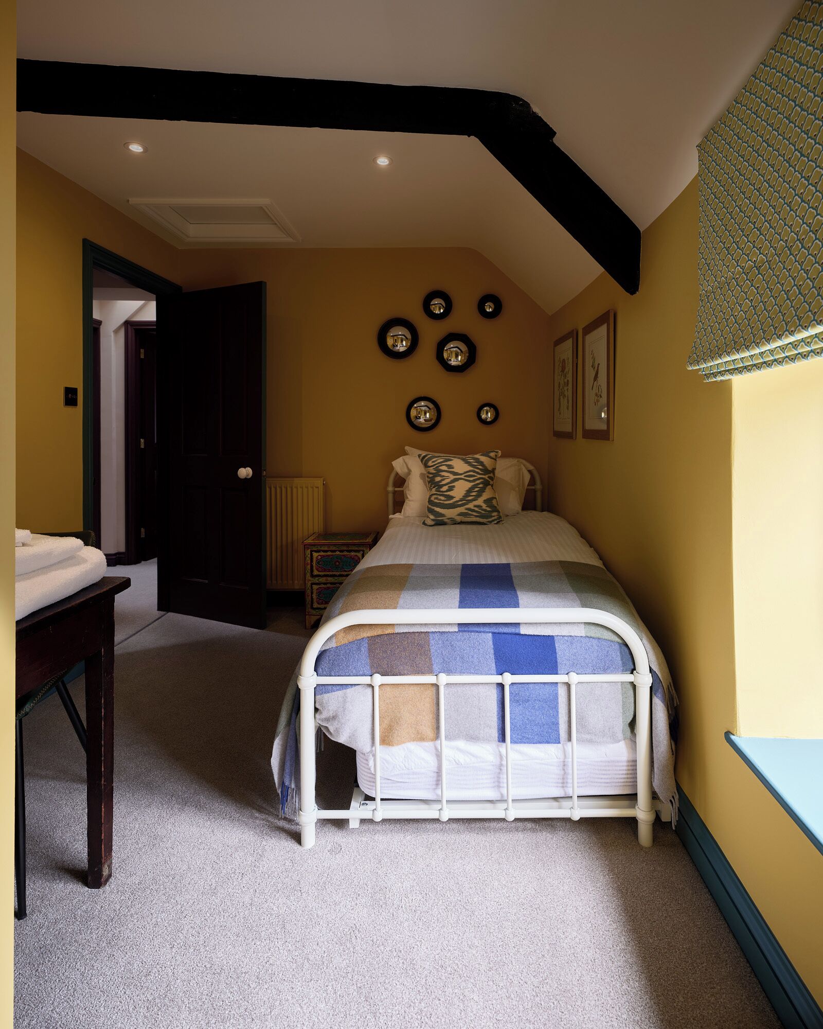 Un dormitorio con cama, mesita de noche, radiador y una pared con espejos circulares y cuadros enmarcados.