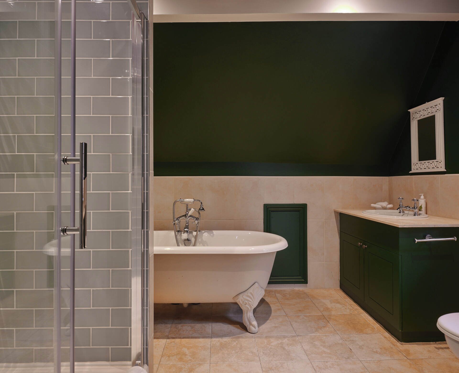 A bathroom with a freestanding bathtub, a glass shower enclosure, and a green vanity with a sink.