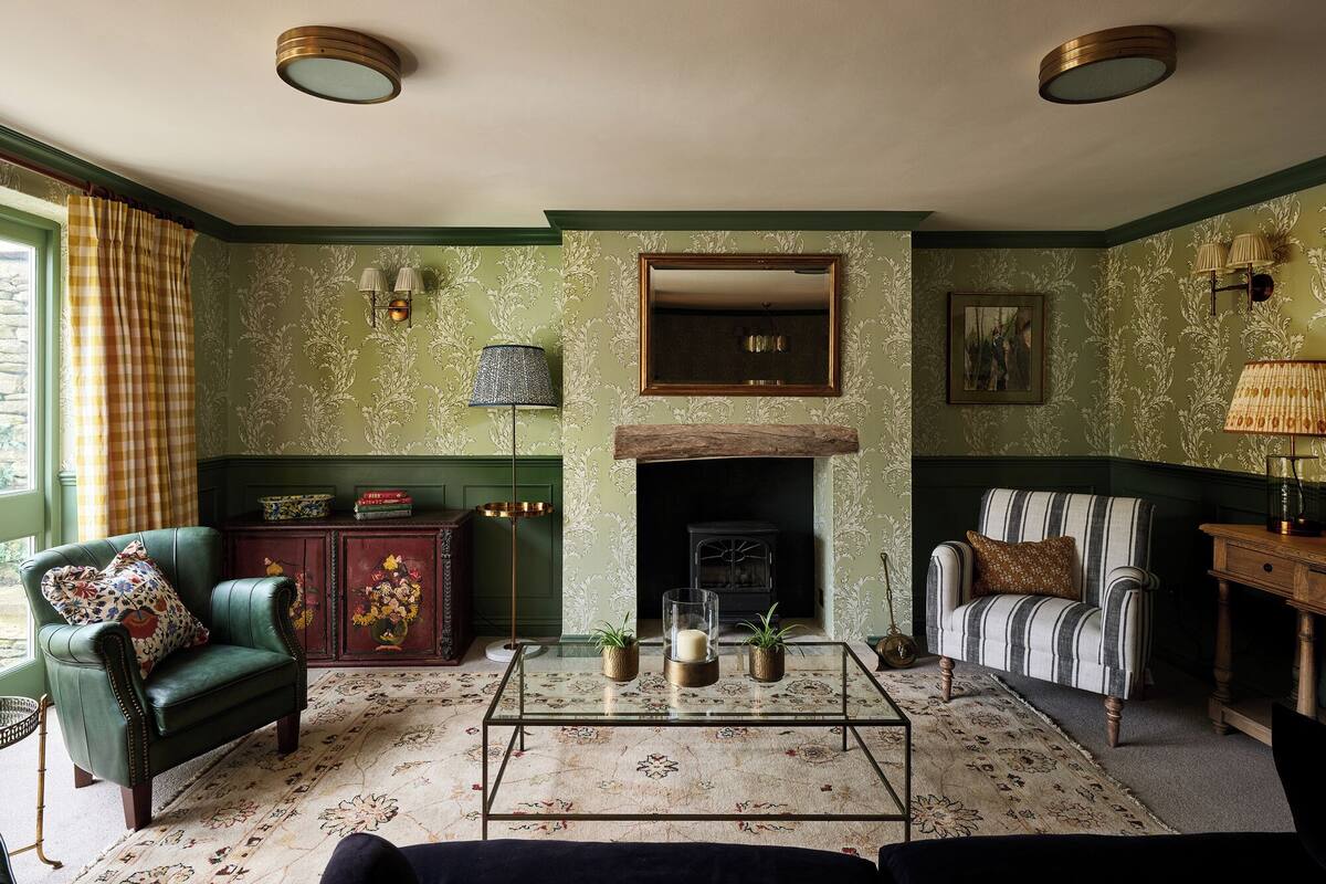 A traditional living room with a fireplace, green walls, and classic furniture.