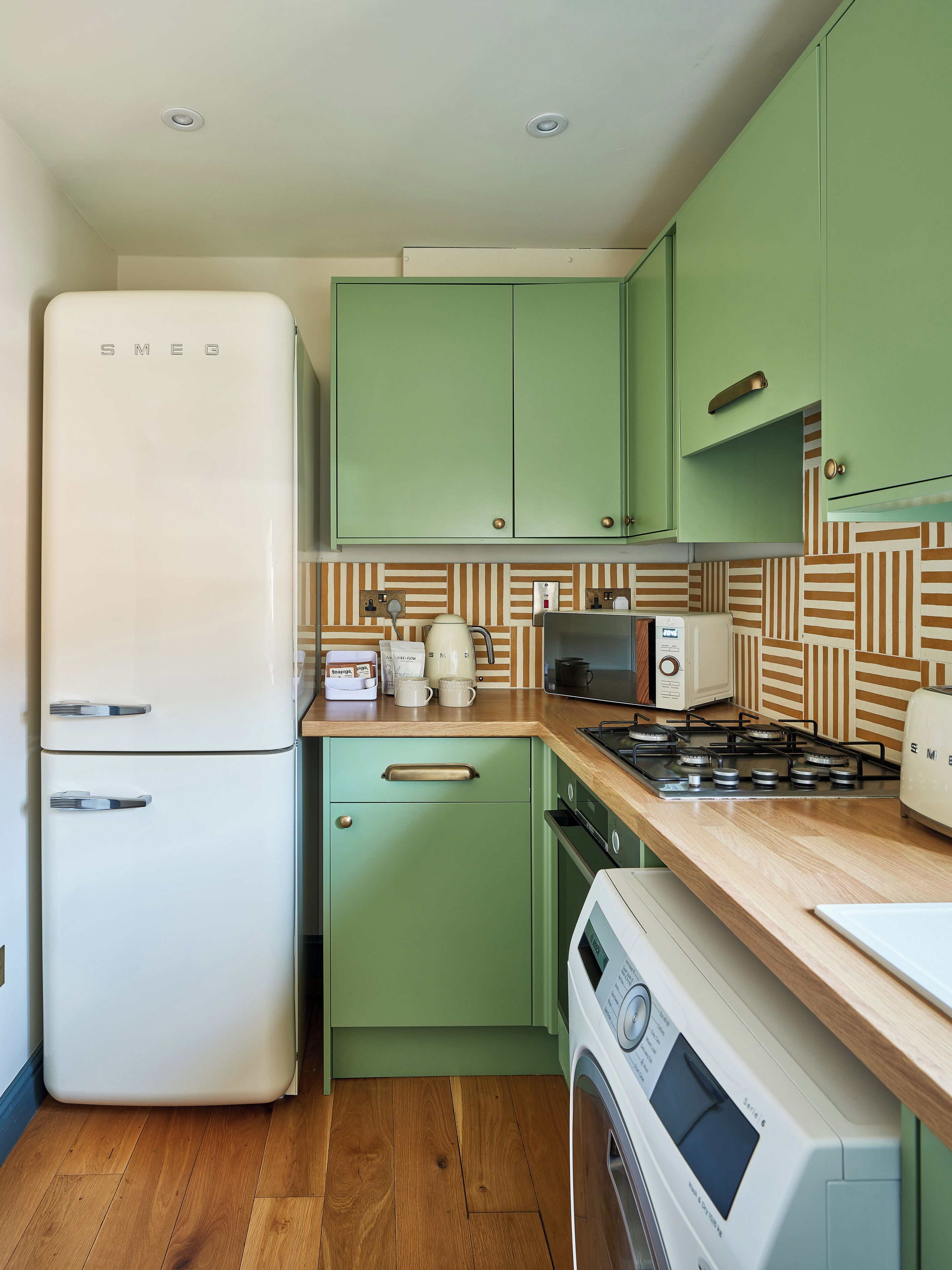 A compact kitchen with a refrigerator, microwave, stove, and washing machine.