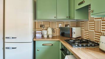 A compact kitchen with a refrigerator, microwave, stove, and washing machine.