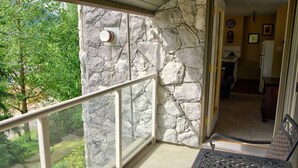 Ein Balkon mit Steinmauer, Metallgeländer und Blick auf Grünflächen.