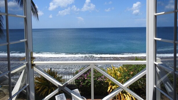 A view from a balcony overlooking the ocean with a clear sky.