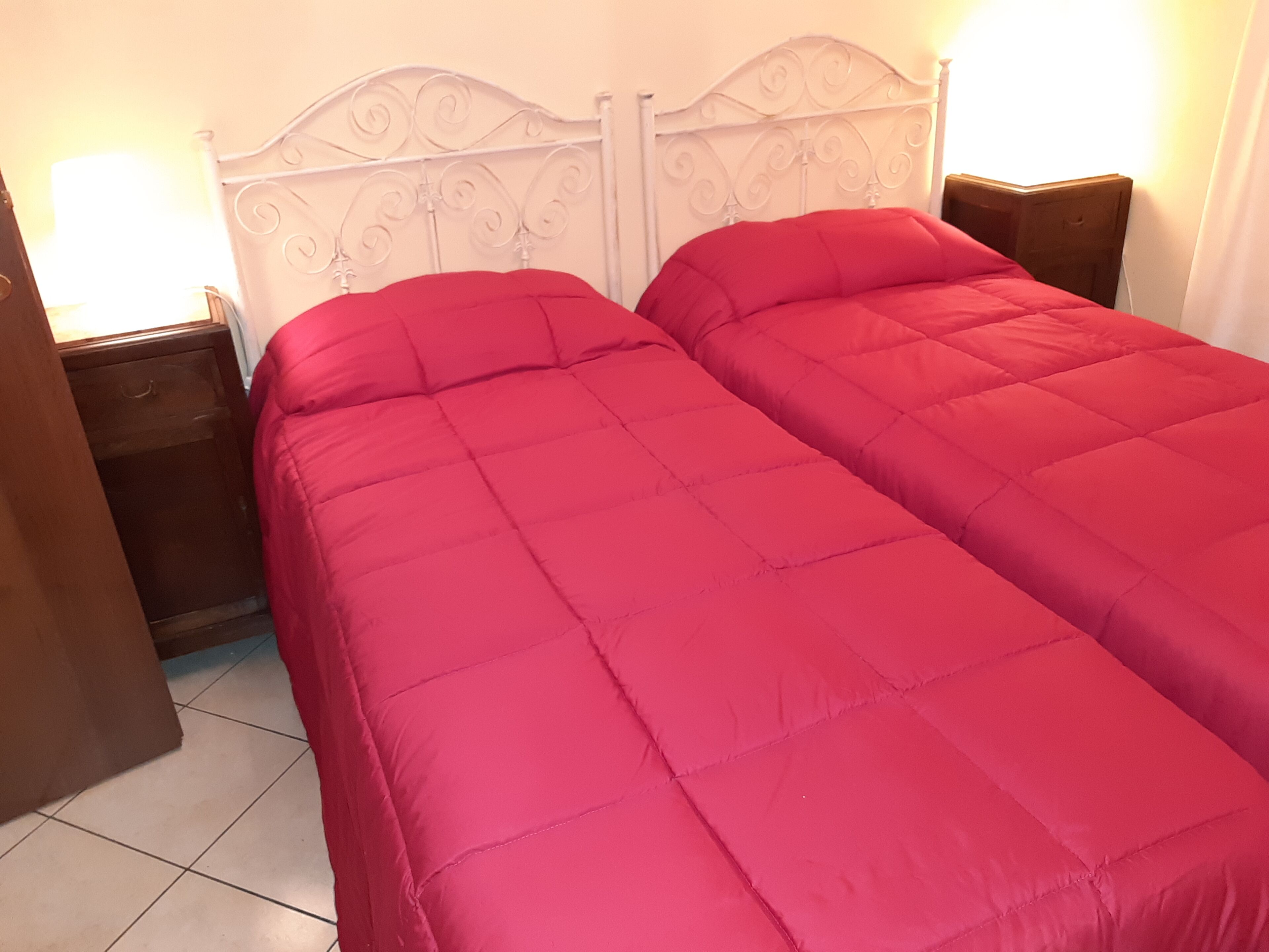 A room with a bed featuring a white metal headboard and two nightstands on either side.