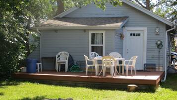 A small house with a porch, a table, and chairs.