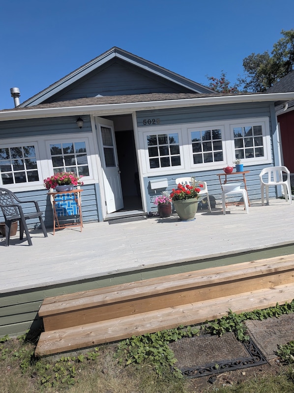 A building with a number 5025, a porch with chairs, and potted plants.