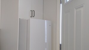 A kitchen with white cabinets, a white refrigerator, and a door with a window.