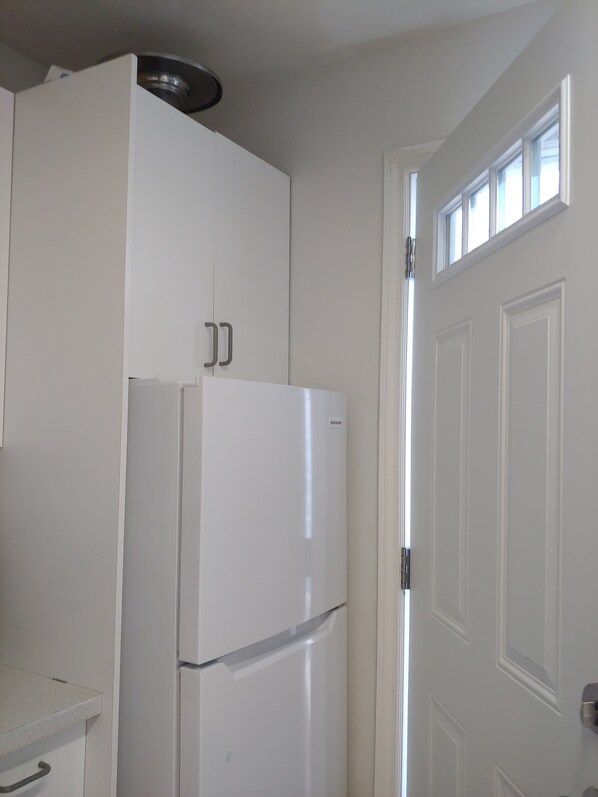 A kitchen with white cabinets, a white refrigerator, and a door with a window. - LINDA  GAYE'S HISTORIC  COTTAGE NEAR BEACH & PROMENADE  STAR # O4298 (Sylvan Lake)