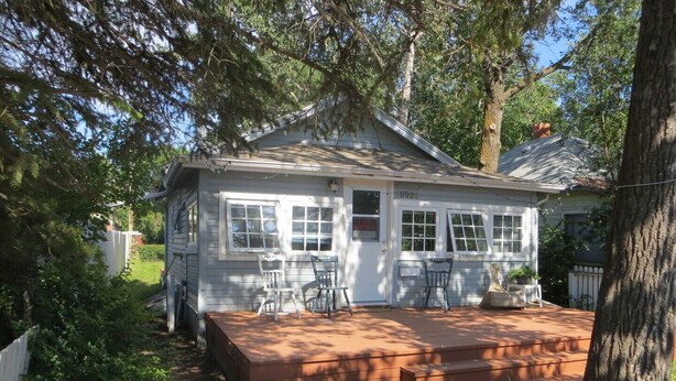 A white house with a porch, two chairs, and a small table.