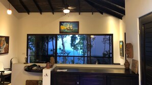 Une pièce dotée d’une grande fenêtre, d’un ventilateur de plafond et d’un tableau accroché au-dessus de la fenêtre.