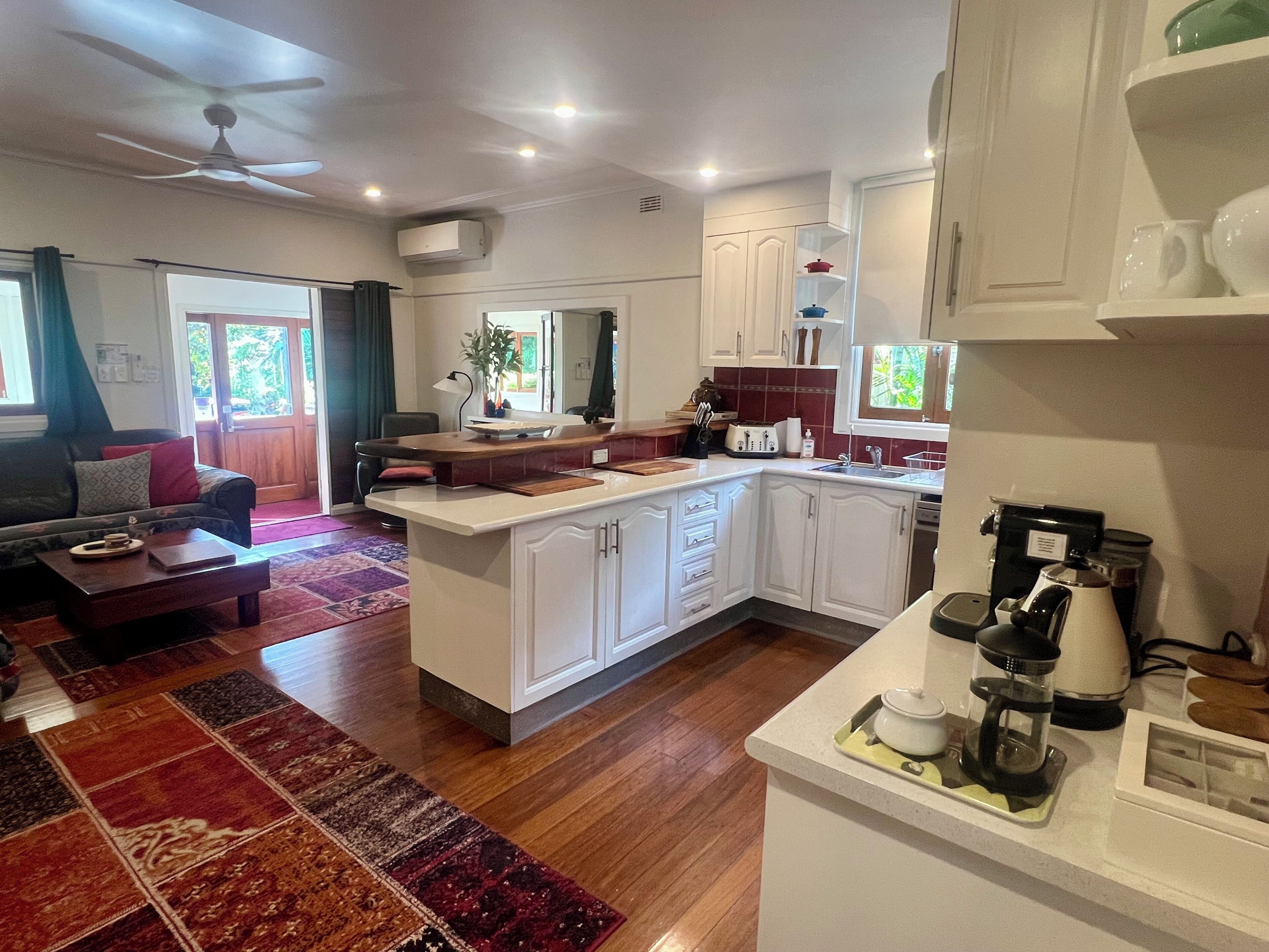 A modern kitchen with white cabinetry, a central island, and a coffee machine.