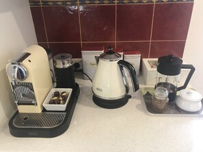 A coffee station with a coffee maker, grinder, kettle, and coffee beans.