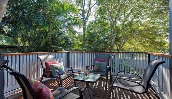 Relax in a serene outdoor space surrounded by lush greenery, with a comfortable seating area and a wooden deck.