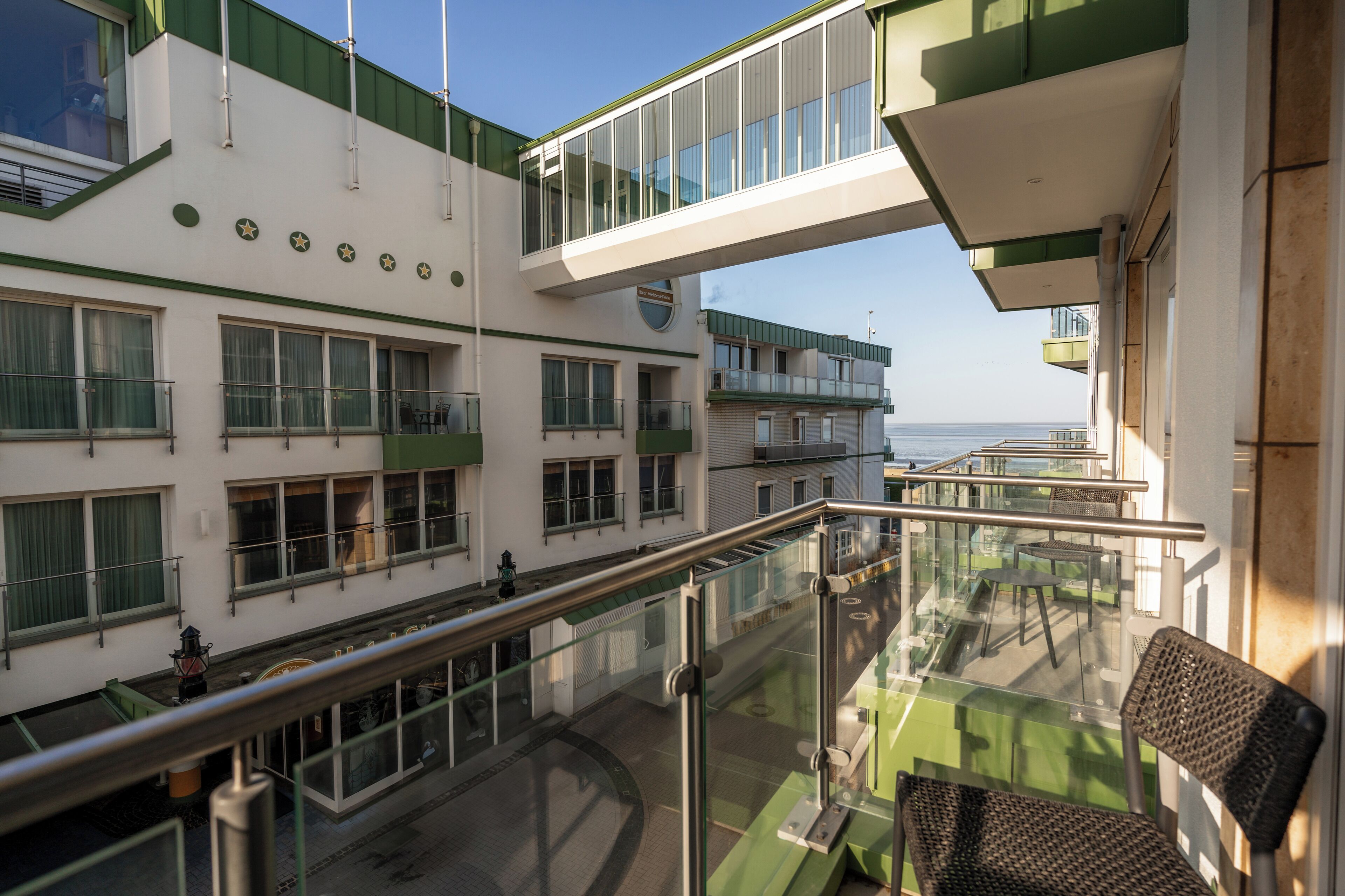 Un hôtel à plusieurs étages doté d’une balustrade en verre, d’un espace extérieur aménagé et offrant une vue sur la mer.