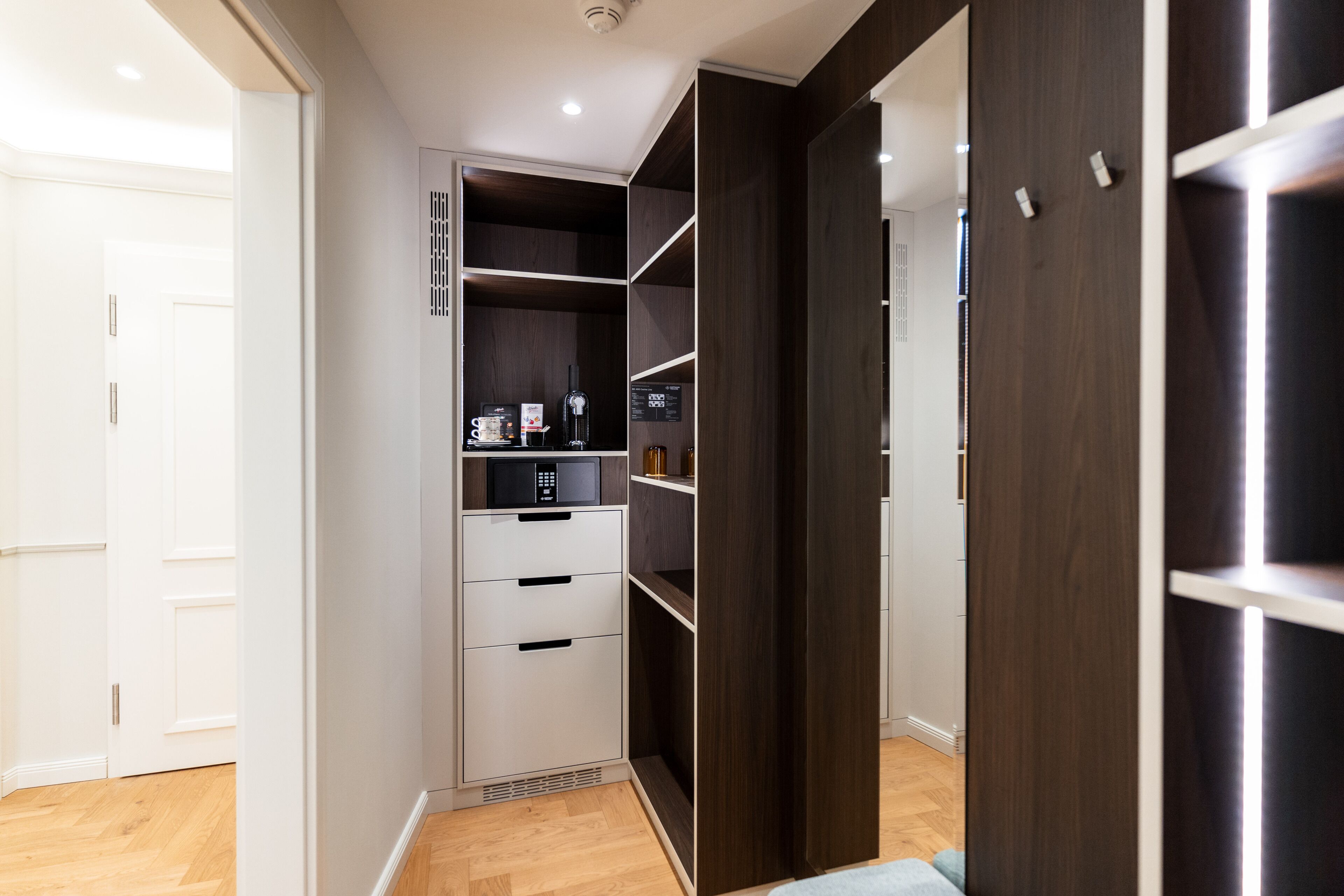 A modern closet with white and dark wood shelving, a microwave, and a small appliance.