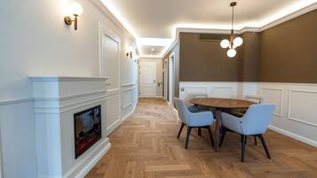 A modern dining area with a wooden herringbone floor, a round table, and two light blue chairs.