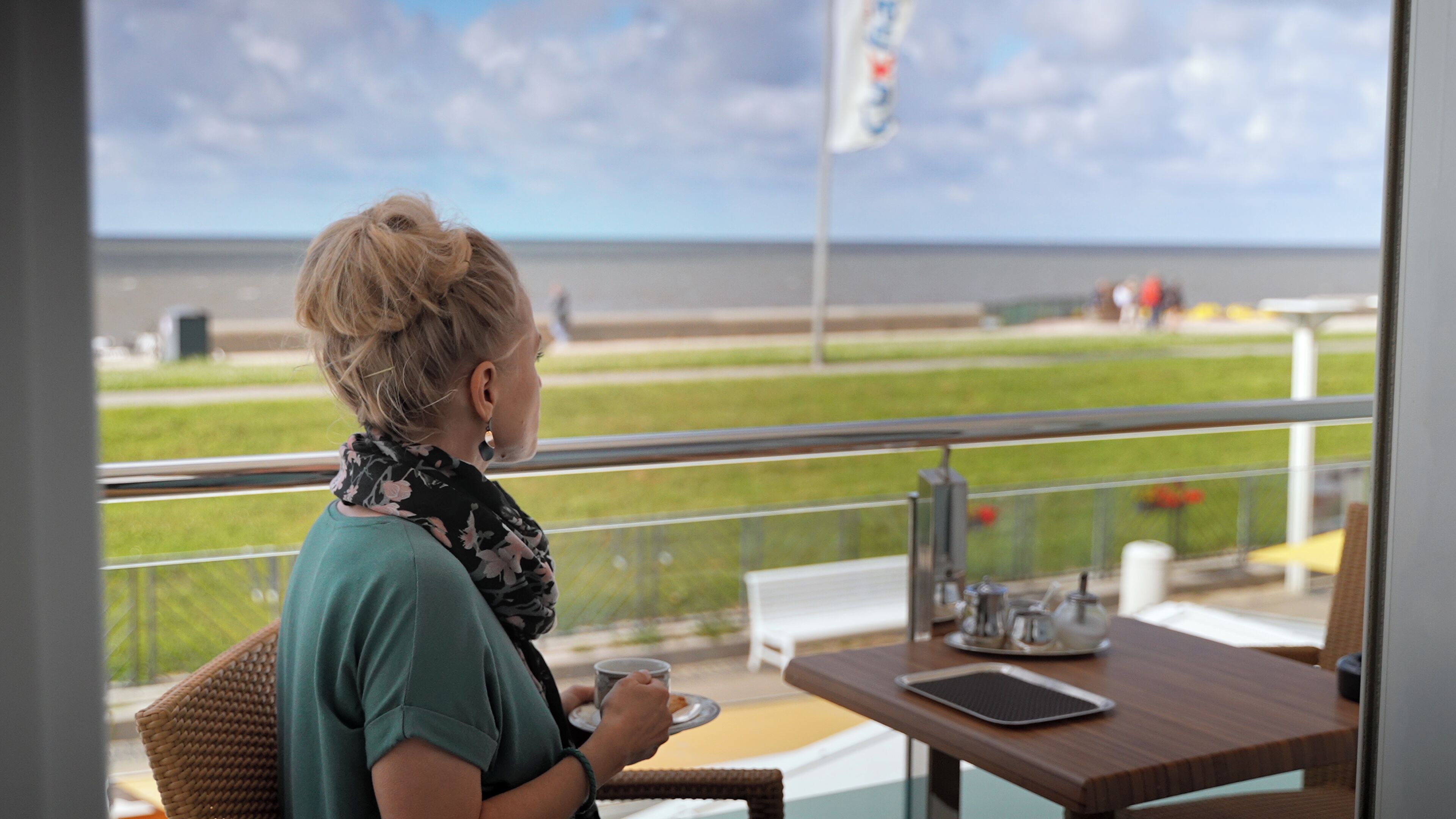 Eine Person sitzt an einem Tisch mit Blick auf das Meer.