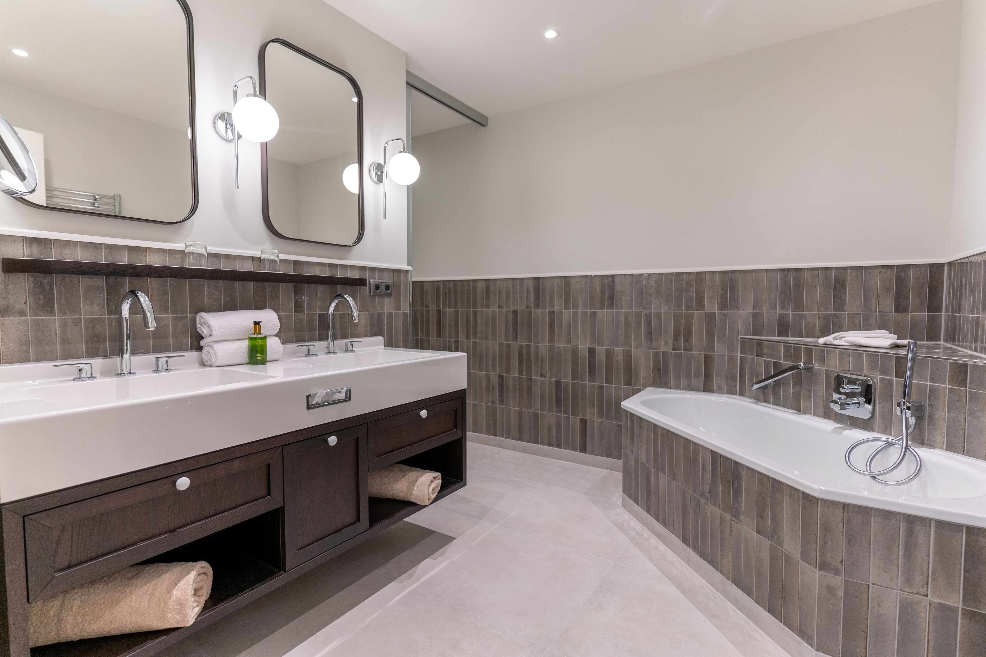 A modern bathroom with a double sink vanity, a large mirror, and a freestanding bathtub.