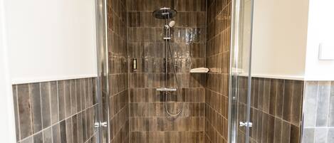 A walk-in shower with a glass door, tiled walls, and a handheld showerhead.
