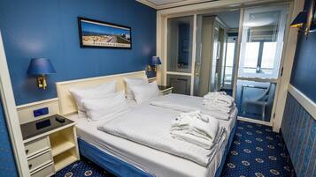 A hotel room with a large bed, two bedside tables, a nightstand, a mirror, and a door leading to a bathroom.