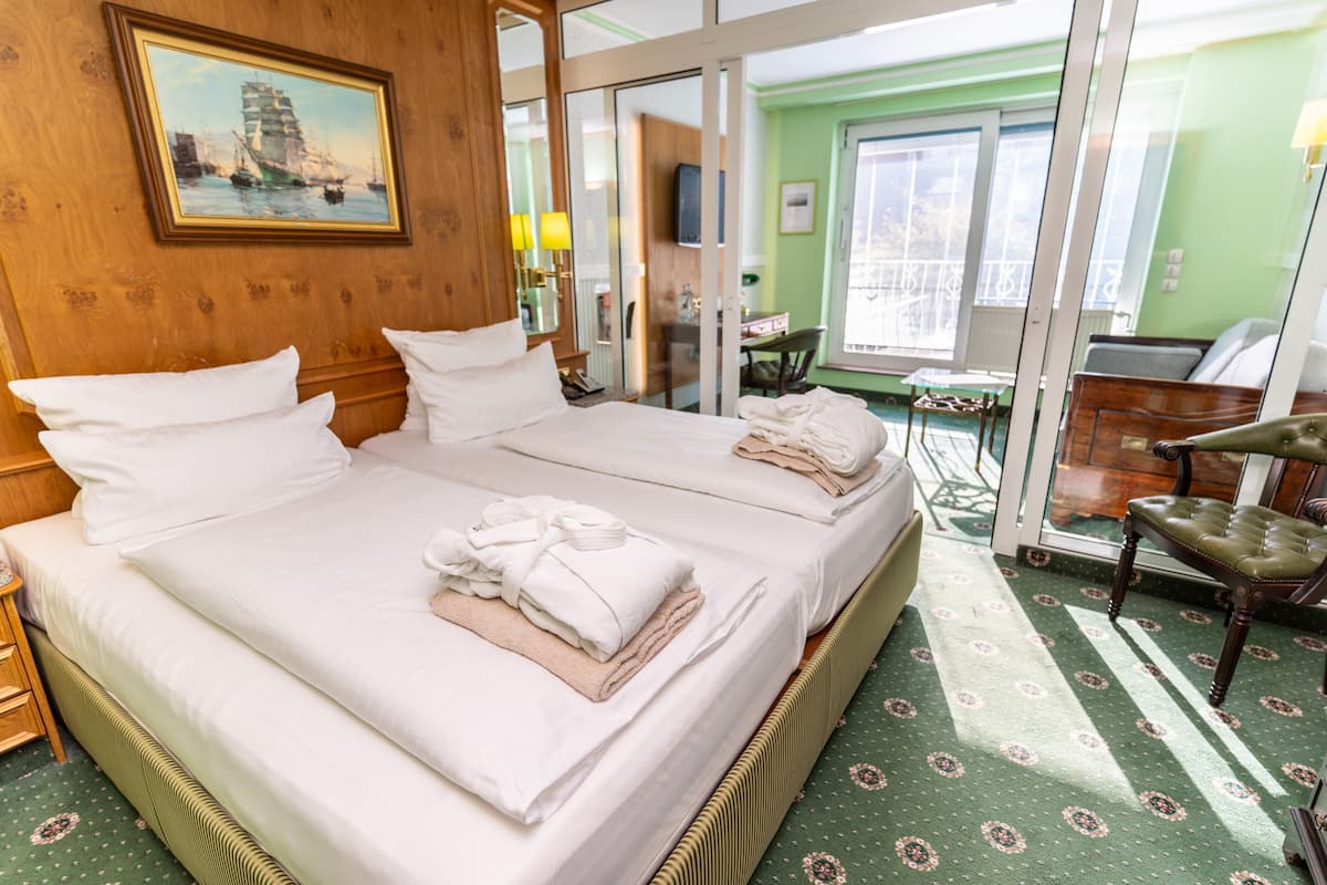 Habitación de hotel con una cama grande, una silla, un escritorio y vistas al exterior.