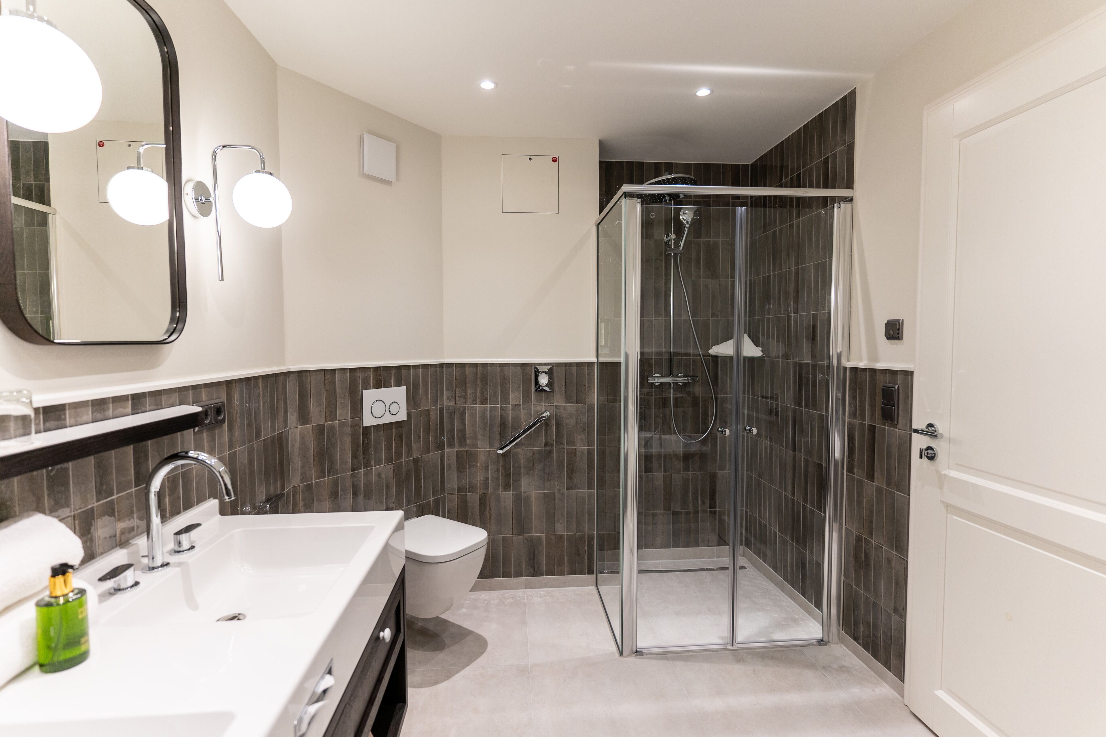 A modern bathroom with a glass-enclosed shower, a white sink, and a toilet.