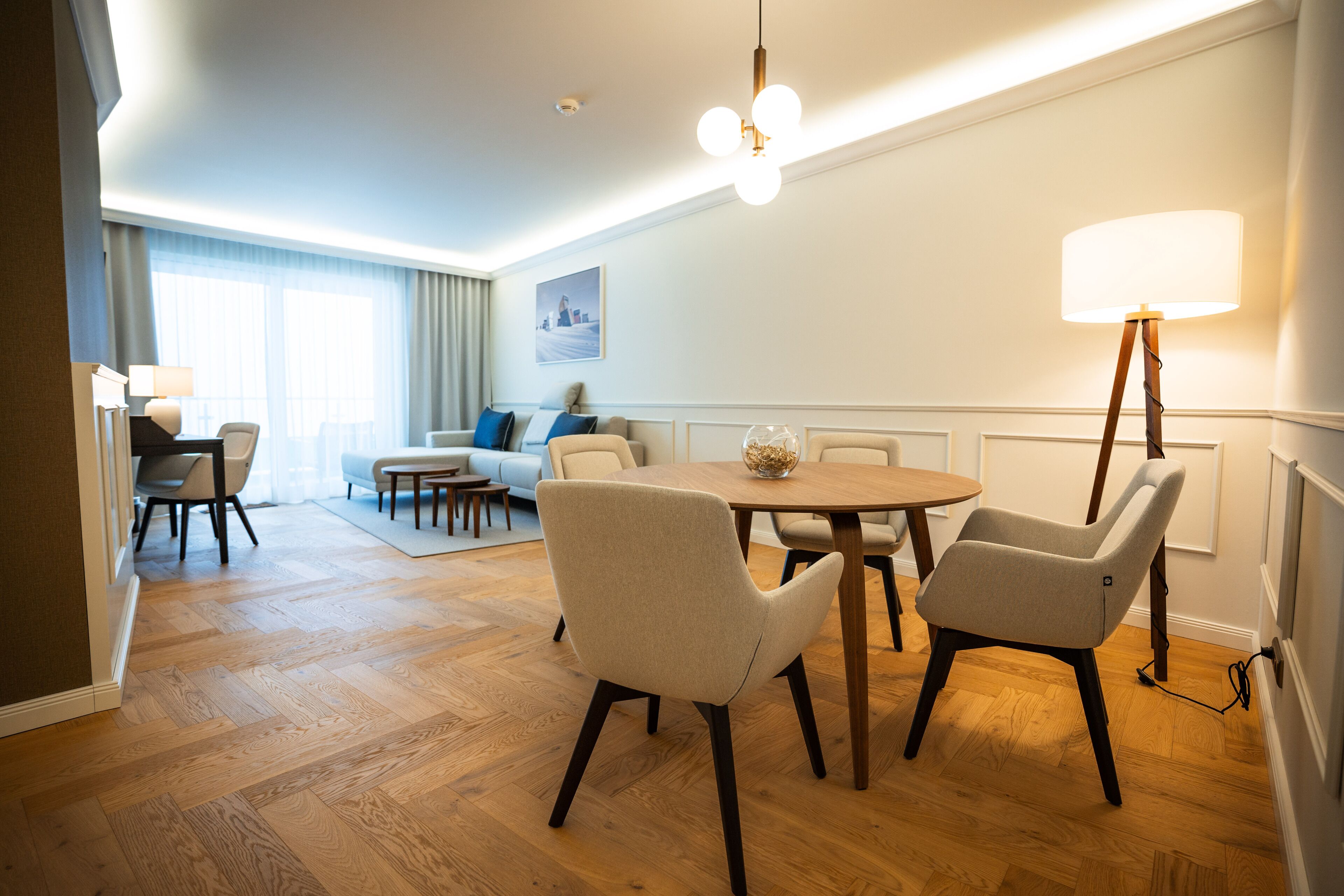 Ein modernes Hotelzimmer mit Essbereich, einer Couch und einer Lampe.