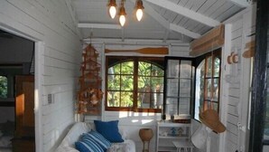 A cozy room with a white bed, a desk, and a large window with a view of trees.