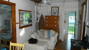A room with a bed, a desk with a computer, a ceiling fan, and a window.