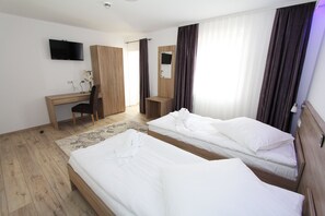 A hotel room with two beds, a desk, a chair, a TV, and a mirror. - Pension Villa Colosseo (Meiningen)
